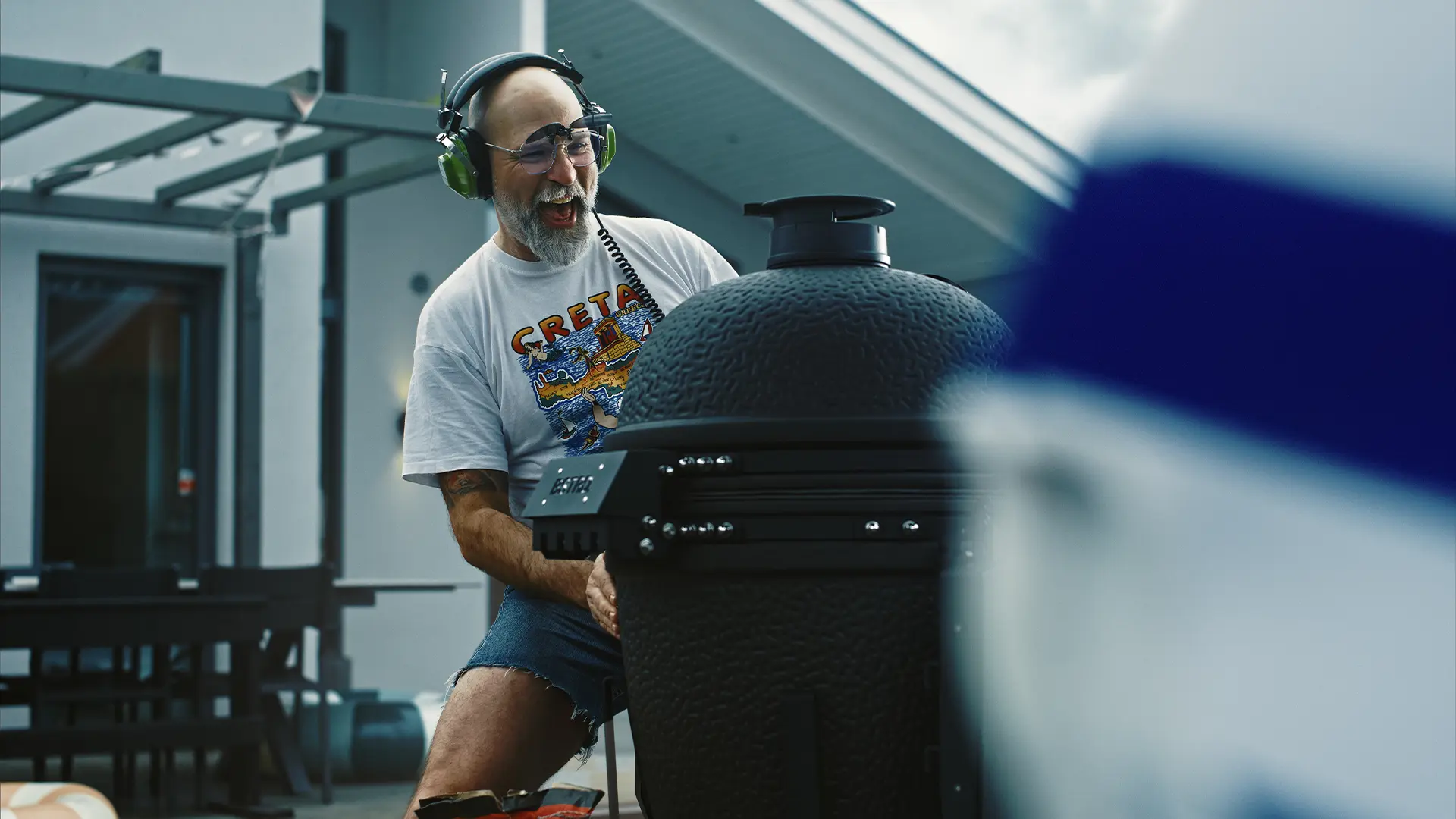 En nöjd man med hörlurar öppnar locket på en kamadogrill