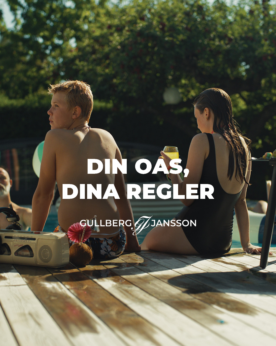 Annons med rubriken Din oas, dina regler: två barn sitter på trädäcket vid poolkanten med en bergsprängare och en drink