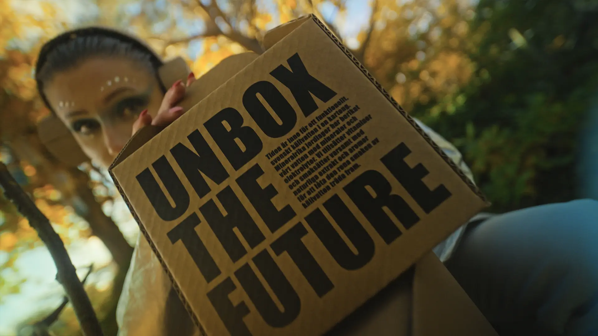 En kvinna kikar fram bakom en kartong med texten Unbox the future